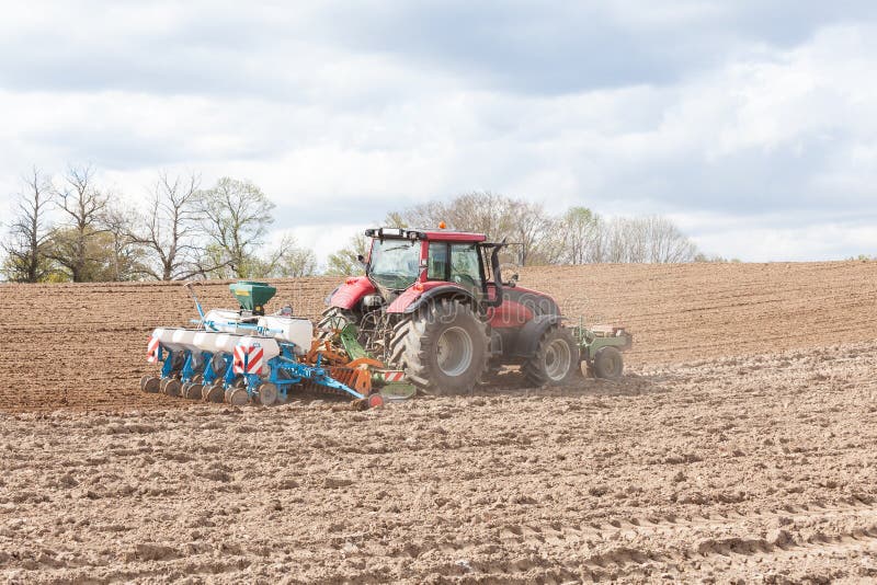 Farmer planting and seeding the spring crop with a five row agricultural planter in a newly ploughed , or plowed, field. Farmer planting and seeding the spring crop with a five row agricultural planter in a newly ploughed , or plowed, field