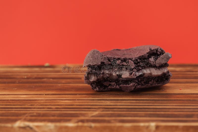 Фиолетовый цвет сдержанного macaron на деревянной таблице в красной пастели i стоковые изображения rf Фиолетовый цвет сдержанного macaron на деревянной таблице в красной пастели i стоковые изображения rf