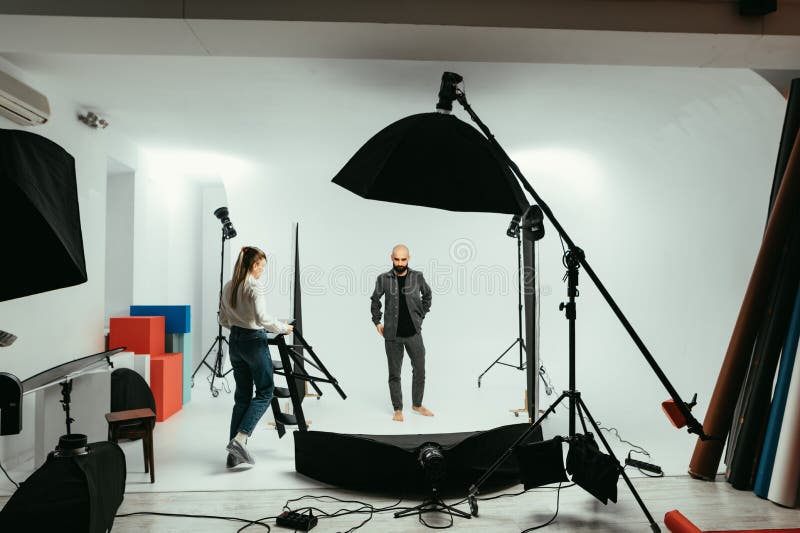 фото за кулисами фотограф и фотомодель, работающая в фотостудии на белом фоне стоковые фото