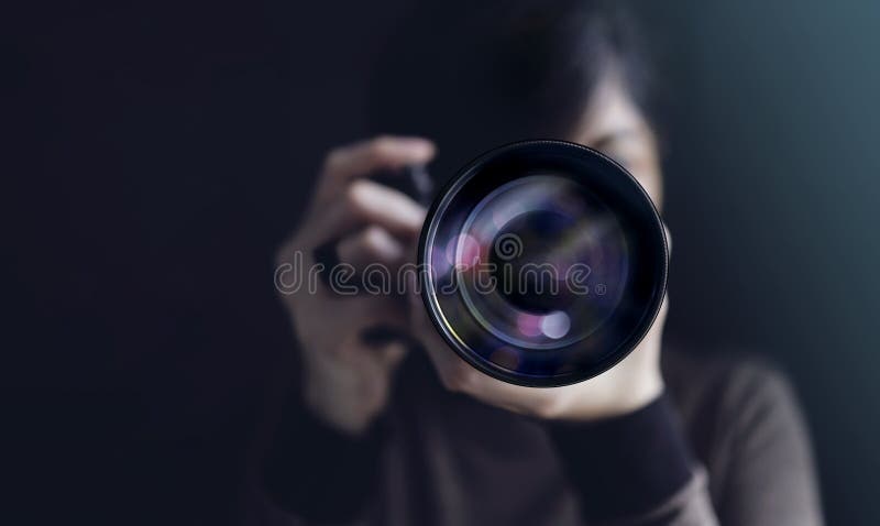Фотограф, берущий самопортрет Женщина, использующая камеру для получения фотографии Темный тон, вид спереди Выборочная фокусировк