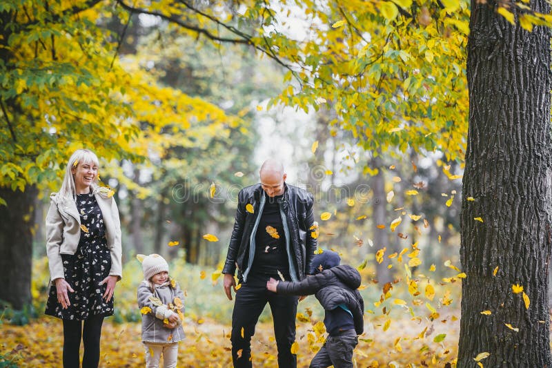 Фотографии счастливой семьи в родителях парка осенью с бодрыми младенцами, играя в лесу падения стоковые фотографии rf