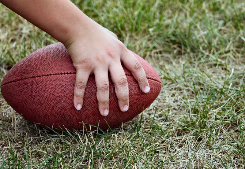 Youth playing American football, hand on the ball ready to snap it. Youth playing American football, hand on the ball ready to snap it.