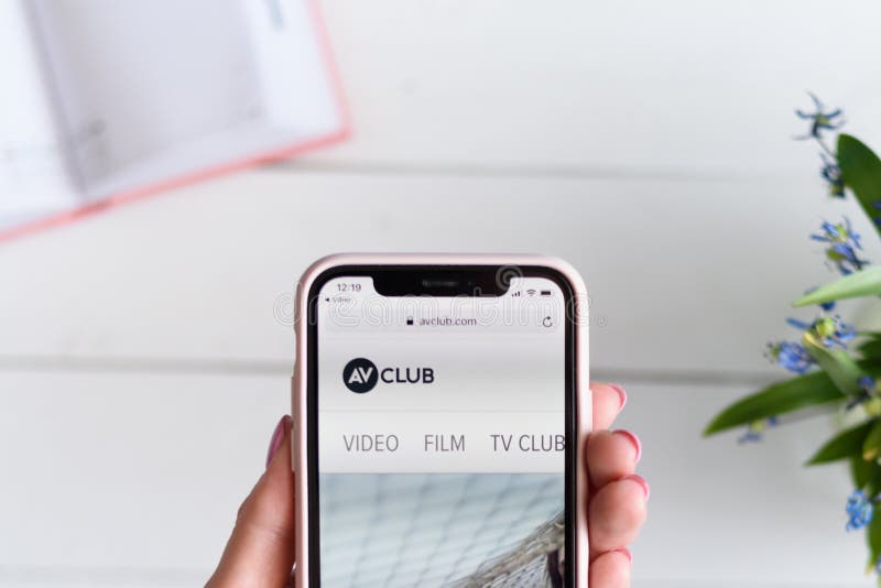 ХАРЬКОВ, УКРАИНА - 10-ое апреля 2019: IPhone x Яблока в женской руке с avclub место com на экране стоковое фото rf