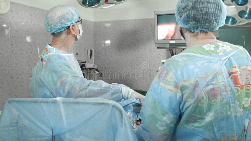 Хирурги следовать laparoscopic хирургией, смотря экран стоковая фотография Хирурги следовать laparoscopic хирургией, смотря экран стоковая фотография