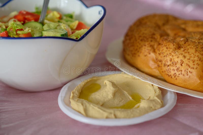 Хлеб Challah на таблице для еды Shabbat и традиционное домодельное hummus, салат на розовой таблице Еврейская кухня стоковое фото Хлеб Challah на таблице для еды Shabbat и традиционное домодельное hummus, салат на розовой таблице Еврейская кухня стоковое фото