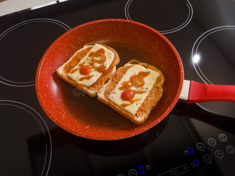 Хлебы в красной сковороде на индукции Cooktop стоковые изображения Хлебы в красной сковороде на индукции Cooktop стоковые изображения