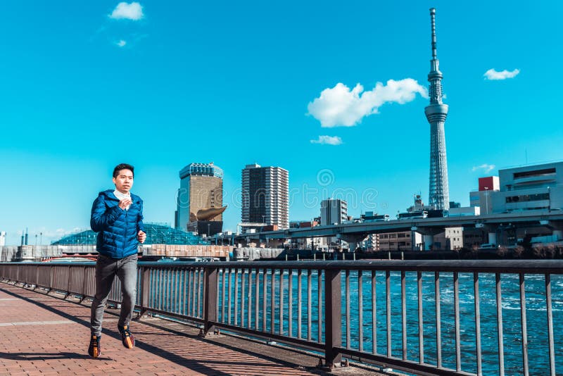Ход человека рекой Sumida, Токио Skytree в предпосылке Тренировка спорта, здоровый образ жизни, или Токио концепция 2020 лет олим стоковая фотография Ход человека рекой Sumida, Токио Skytree в предпосылке Тренировка спорта, здоровый образ жизни, или Токио концепция 2020 лет олим стоковая фотография