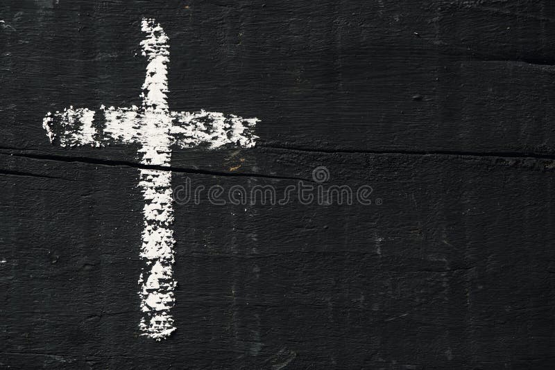 Closeup of a christian cross painted with chalk on a rustic dark gray wooden surface, with a blank space on the right. Closeup of a christian cross painted with chalk on a rustic dark gray wooden surface, with a blank space on the right