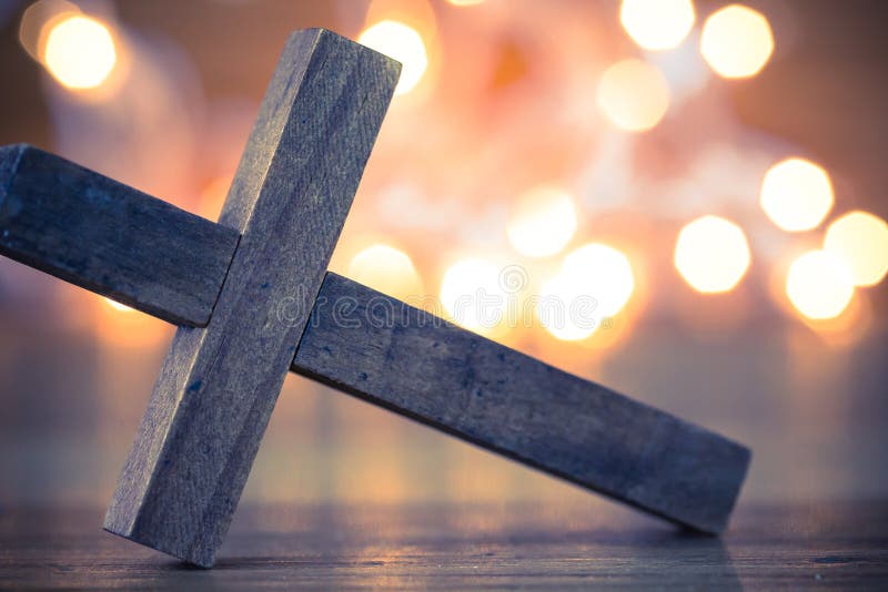 A wooden Christian cross with a soft bokeh lights background. A wooden Christian cross with a soft bokeh lights background.