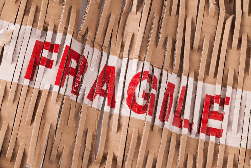 Fragile tape label across cardboard shredded packaging. Fragile tape label across cardboard shredded packaging