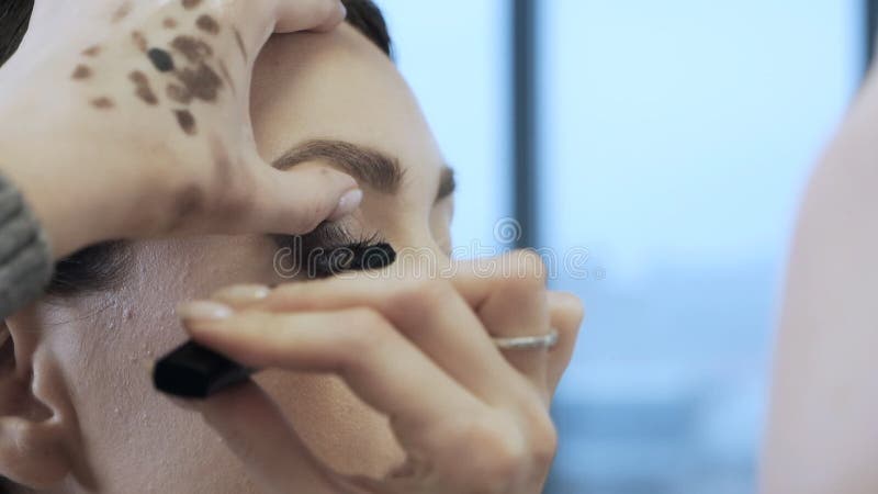 художники-макияж руки применяют тушкару с моделями кисти лицом к лицу на красивой модели. индустрия красоты видеоматериал