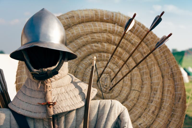 Abstract archers helmet, kettle hat and gambeson, defensive jacket/ against the target with three arrows. Abstract archers helmet, kettle hat and gambeson, defensive jacket/ against the target with three arrows.