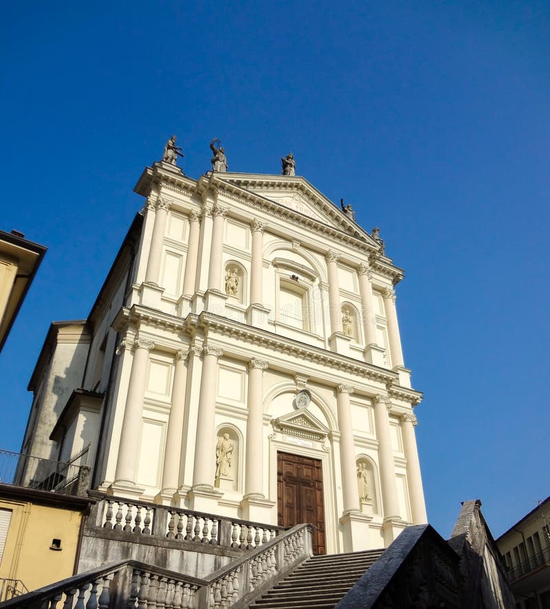 The church Santa Margarita in the town of Valli del Pasubio lightened by the sun, blue sky background. The church Santa Margarita in the town of Valli del Pasubio lightened by the sun, blue sky background