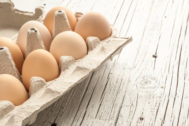 Цыпленок eggs в картонной коробке на белой деревянной предпосылке стоковая фотография rf Цыпленок eggs в картонной коробке на белой деревянной предпосылке стоковая фотография rf