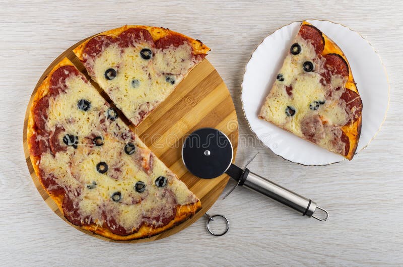Части испеченных pepperoni пиццы на разделочной доске, резце пиццы, части пиццы в плите на таблице r стоковые фотографии rf Части испеченных pepperoni пиццы на разделочной доске, резце пиццы, части пиццы в плите на таблице r стоковые фотографии rf