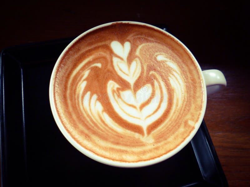 Чашка горячих latte или капучино с завораживающим искусством latte стоковая фотография Чашка горячих latte или капучино с завораживающим искусством latte стоковая фотография