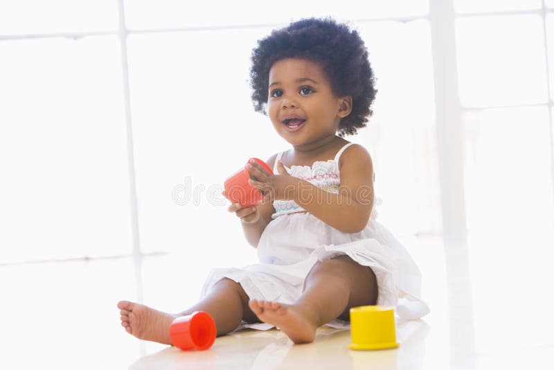 Baby indoors playing with cup toys smiling. Baby indoors playing with cup toys smiling