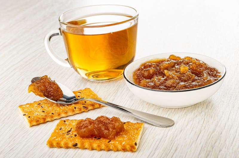 чашка с чайной ложкой с джемом в тарелке с печеньем с яблочным вареньем и варенье на деревянном столе стоковое изображение