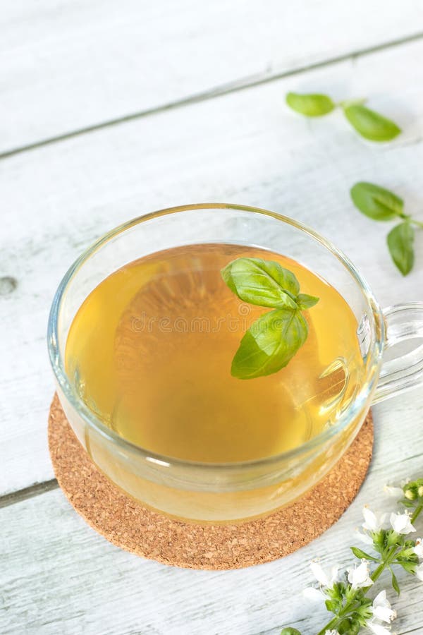 Cup of fresh basil tea on wooden table. Hot herbal drink with yellow color. Close-up. Selective focus. Cup of fresh basil tea on wooden table. Hot herbal drink with yellow color. Close-up. Selective focus.