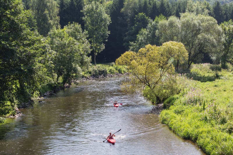 Человек и женщина в каяке на реке Ourthe около Roche-en-Ardenne Ла, Бельгии стоковая фотография rf Человек и женщина в каяке на реке Ourthe около Roche-en-Ardenne Ла, Бельгии стоковая фотография rf
