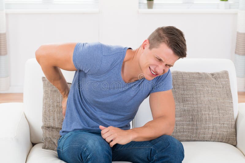 Человек на софе страдая от Backpain стоковое фото Человек на софе страдая от Backpain стоковое фото