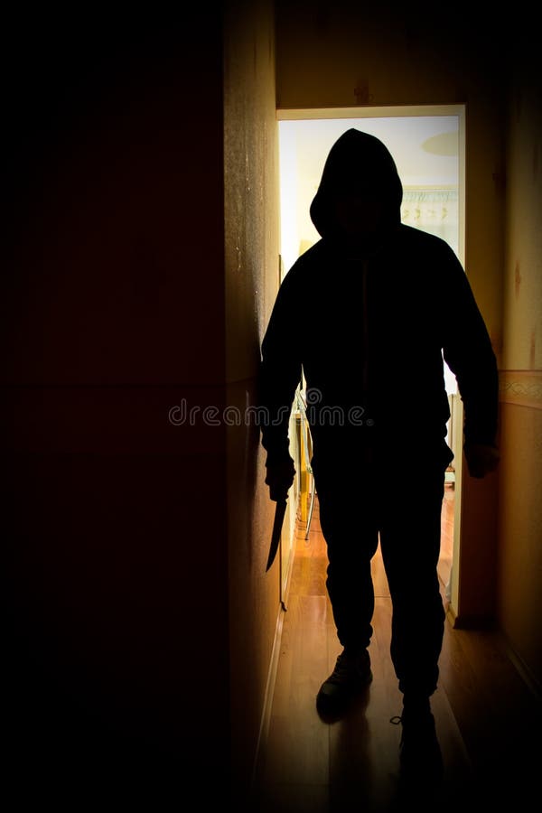 A man standing in a hallway with a knife. A man standing in a hallway with a knife