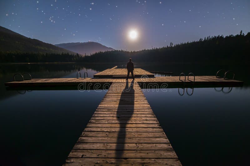 Человек смотря луну на доке в Whistler стоковая фотография rf Человек смотря луну на доке в Whistler стоковая фотография rf