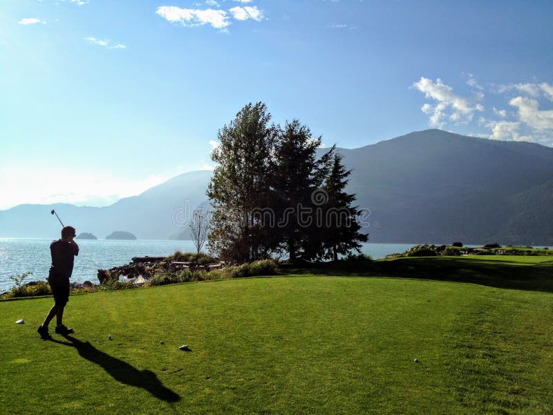 Человек VA играя гольф вдоль океана в Howe Sound, Британской Колумбии, Канаде Красивый солнечный день стоковое фото rf Человек VA играя гольф вдоль океана в Howe Sound, Британской Колумбии, Канаде Красивый солнечный день стоковое фото rf