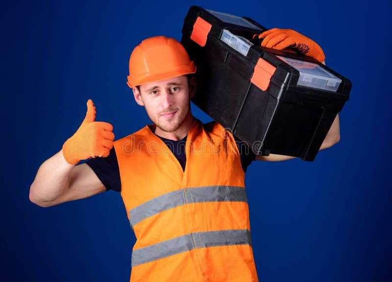 Человек в шлеме, трудная шляпа держит toolbox и показывает что большой палец руки вверх показывать, голубая предпосылка Отремонти стоковая фотография Человек в шлеме, трудная шляпа держит toolbox и показывает что большой палец руки вверх показывать, голубая предпосылка Отремонти стоковая фотография