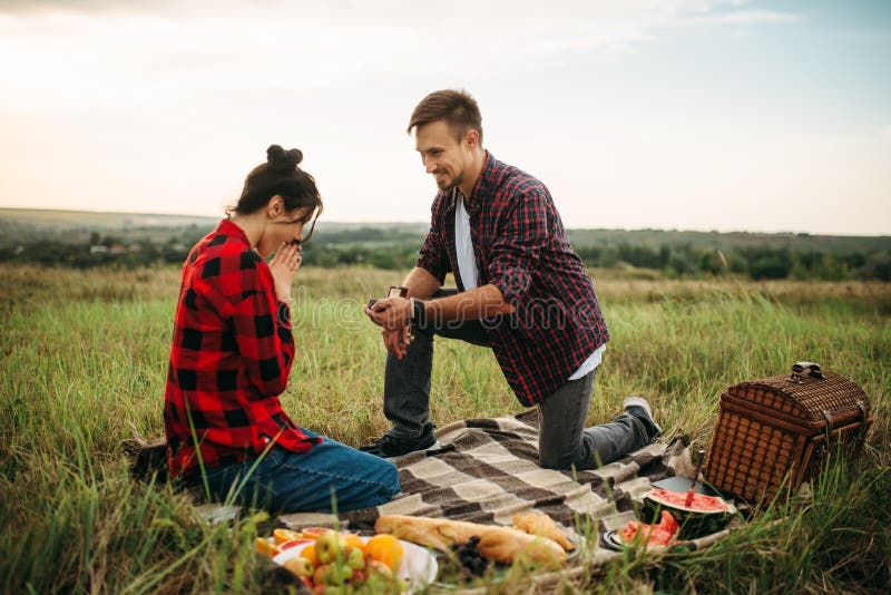 Man makes a marriage proposal on romantic picnic in summer field. Junket of men and woman, happy moments. Man makes a marriage proposal on romantic picnic in summer field. Junket of men and woman, happy moments