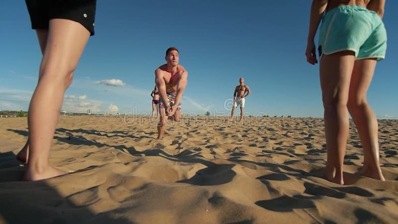 Человек летает вверх в воздух, делает переход шарика пока играющ волейбол пляжа и падает на песок