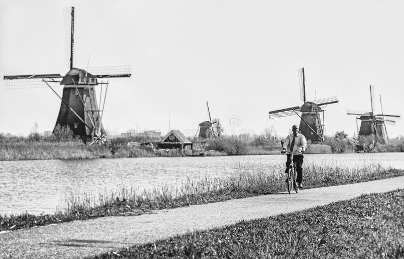 KINDERDIJK, NETHERLANDS - APRIL 1: Senior man on bike and windmills at open air musem at Kinderdijk on April 1, 2014 in Kinderdijk. KINDERDIJK, NETHERLANDS - APRIL 1: Senior man on bike and windmills at open air musem at Kinderdijk on April 1, 2014 in Kinderdijk