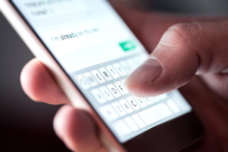 Человек отправляя текстовое сообщение и sms со смартфоном Гай отправляя SMS и используя мобильному телефону последнему вечером в Человек отправляя текстовое сообщение и sms со смартфоном Гай отправляя SMS и используя мобильному телефону последнему вечером в