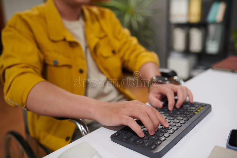 Closeup image of man with disability working on computer in office, answering e-mails and coding. Closeup image of man with disability working on computer in office, answering e-mails and coding