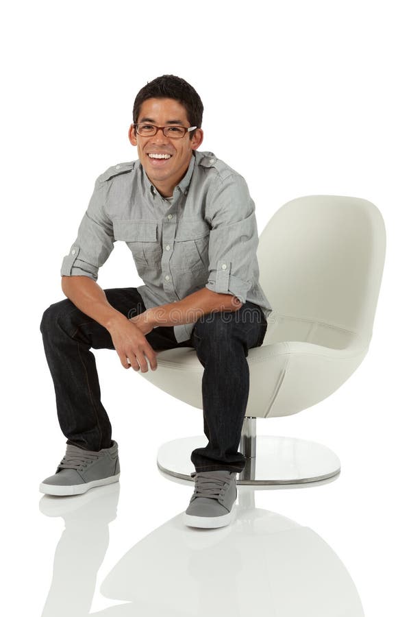 College age man sitting on a modern chair on white. College age man sitting on a modern chair on white