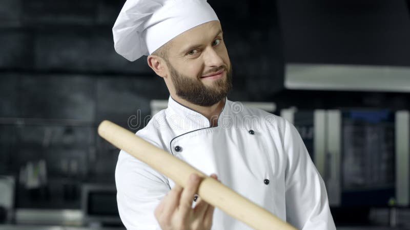 Человек шеф-повара играя с роликом на кухне Портрет профессионального шеф-повара