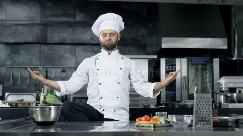 Человек шеф-повара представляя на профессиональной кухне Шеф-повар делая потеху в представлении раздумья