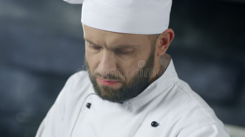 Человек шеф-повара работая на профессиональной кухне Близкая поднимающая вверх сторона шеф-повара варя еду