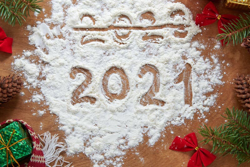 Через 2020, 2021, написанное на муку Снеговика, конусы, ветки ели, раскланялся и подарки на деревянной фон стоковые изображения rf
