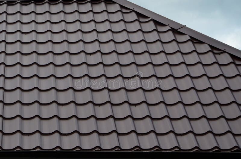 Brown roof tiles or shingles on house as background image. New overlapping brown classic style roofing material texture pattern on a actual house. Brown roof tiles or shingles on house as background image. New overlapping brown classic style roofing material texture pattern on a actual house