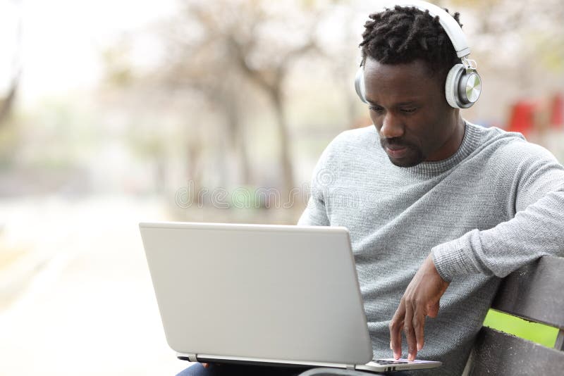 Чернокожий человек с elearning наушников, используя компьютер стоковые изображения