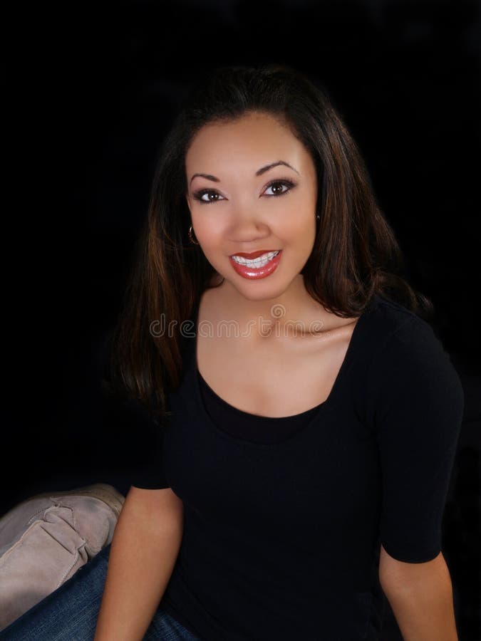 Young woman smiling with braces against dark background. Young woman smiling with braces against dark background