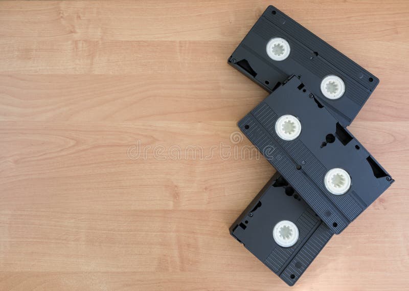 2 black VHS with white spoons lying on a beige wooden background with copy space. 2 black VHS with white spoons lying on a beige wooden background with copy space.