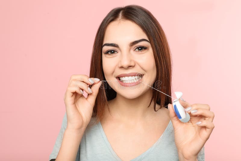 Young woman flossing teeth on color background. Young woman flossing teeth on color background