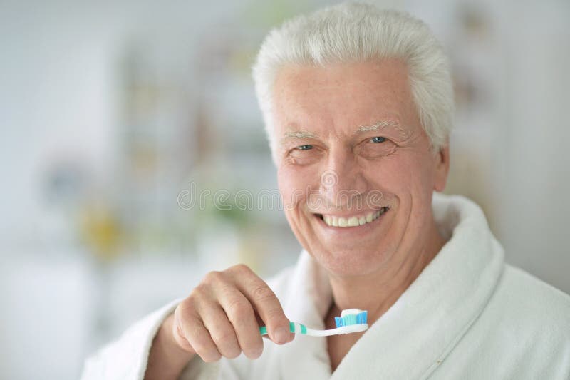 Elderly man brushing his teeth in bathroom. Elderly man brushing his teeth in bathroom