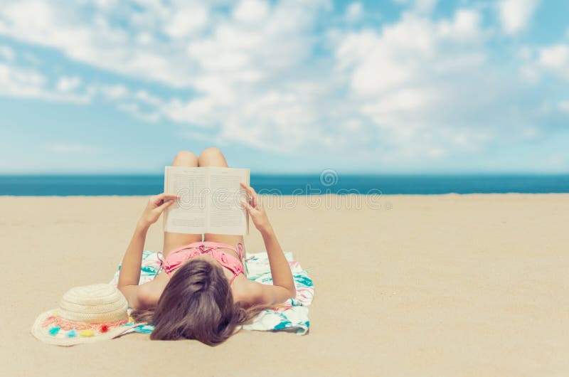 Чтение молодой женщины расслабляющее книга на пляже стоковое фото Чтение молодой женщины расслабляющее книга на пляже стоковое фото