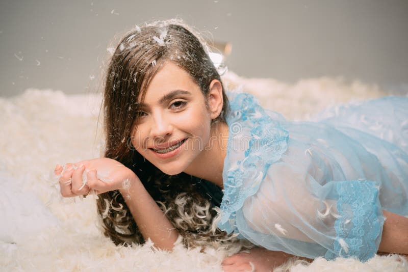 Чувствовать ленивый Милая девушка в женском белье nightie с пером в длинных волосах Милая девушка ослабляя на подушке кровати пер стоковое фото