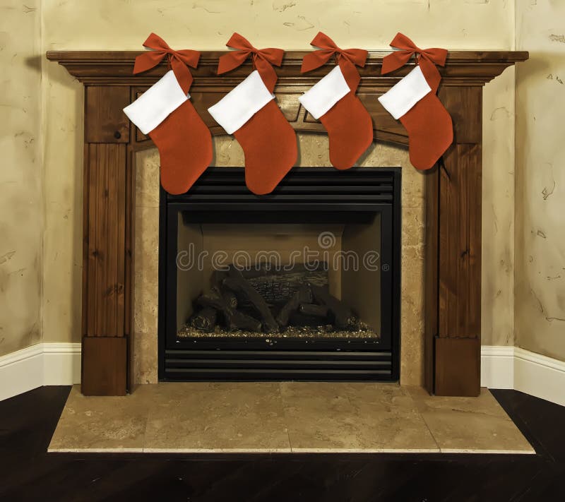 Four red Christmas stockings with bows hanging on fireplace mantel. Four red Christmas stockings with bows hanging on fireplace mantel