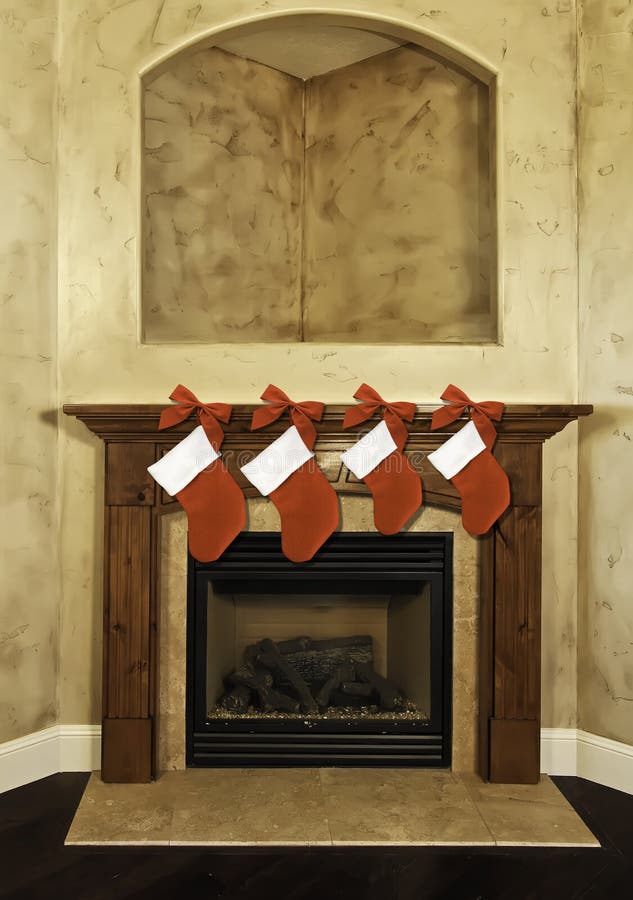 Four red Christmas stockings and red bows hanging along fireplace mantel. Four red Christmas stockings and red bows hanging along fireplace mantel