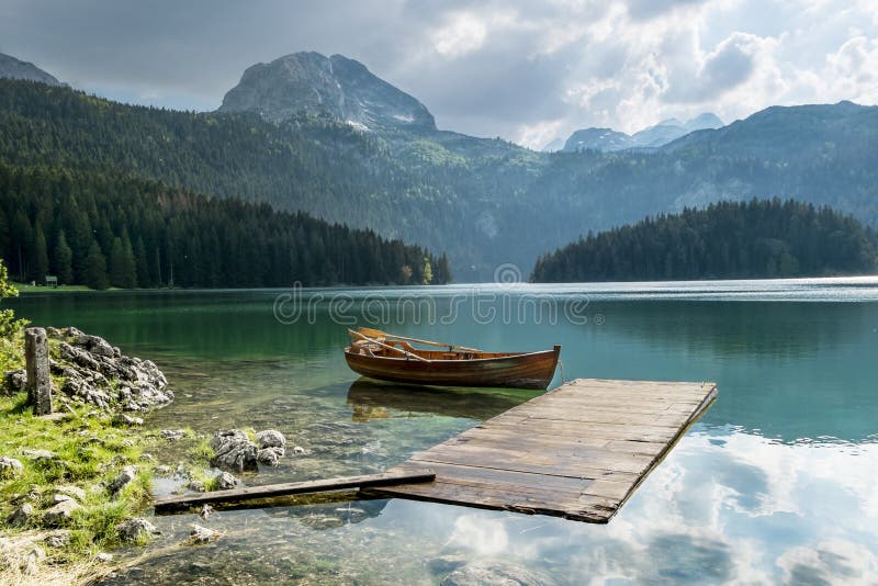 Шлюпка на черном озере в национальном парке Durmitor и горах i стоковое фото rf Шлюпка на черном озере в национальном парке Durmitor и горах i стоковое фото rf